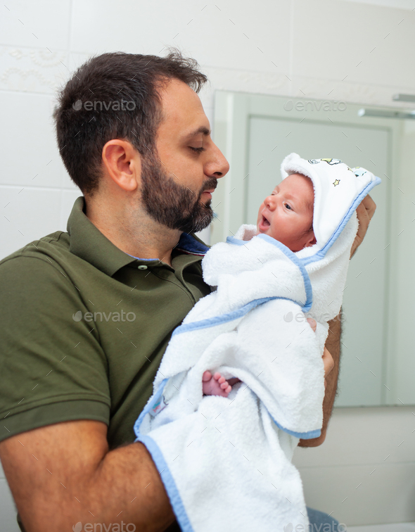 First bath of newborn baby boy. The baby is in the bathrobe in his